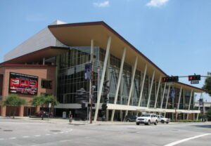 Located in the heart of downtown Houston, Texas, The Hobby Center for the Performing Arts stands as one of the city’s premier cultural destinations. Known for its stunning architecture, world-class performances, and a deep commitment to artistic excellence, the Hobby Center serves as a beacon for the performing arts community in Houston. It is a hub where music, theater, dance, and other performing arts come to life, offering both locals and visitors an unparalleled experience. The Hobby Center was established in 2002 and was named after former Texas Lieutenant Governor William P. Hobby, in recognition of his contributions to the arts. The center was created to address Houston’s growing need for a top-tier performing arts venue and to provide a space for smaller productions to flourish alongside the city’s major performing arts organizations. It has since become a beloved landmark, drawing audiences from all over Texas and beyond. One of the first things visitors notice about the Hobby Center is its breathtaking design. The building, which was designed by renowned architect Robert A.M. Stern, seamlessly blends modern elegance with a nod to Houston’s rich history. The center’s expansive glass windows offer panoramic views of downtown Houston, creating a dynamic interplay between the urban landscape and the architectural masterpiece. The Hobby Center boasts two theaters: the 2,650-seat Sarofim Hall and the more intimate Zilkha Hall, which seats 500. Sarofim Hall is an impressive space with a grand proscenium and excellent acoustics, making it ideal for large-scale productions such as Broadway shows and operas. Zilkha Hall, on the other hand, is perfect for smaller, more experimental productions, allowing local talent to showcase their work in a more intimate setting. The Hobby Center is home to Theatre Under The Stars (TUTS), a renowned Houston-based nonprofit that produces musical theater. TUTS offers a mix of popular Broadway musicals, new productions, and original works, making it a vital part of Houston’s cultural fabric. Over the years, the Hobby Center has hosted a wide array of performances, from touring Broadway shows to concerts, ballet, and more. Beyond TUTS, the Hobby Center welcomes a diverse lineup of performing arts organizations, ensuring that there’s always something new for audiences to enjoy. Whether it's the latest Broadway hit, a classical music concert, or a cutting-edge contemporary dance performance, the center offers a vibrant and dynamic programming schedule. In addition to its outstanding performances, the Hobby Center is committed to making the performing arts accessible to all. Through its various educational outreach programs, the center introduces young people to the arts and fosters the next generation of artists and audiences. One notable initiative is the Tommy Tune Awards, which celebrate excellence in high school musical theater across the Houston area. Named after Houston native and Tony Award-winning actor, dancer, and choreographer Tommy Tune, the awards highlight the immense talent present in local schools. Through this program, the Hobby Center provides a platform for young performers to hone their skills and gain recognition for their work. Additionally, the center offers programs that bring underprivileged children to live performances, ensuring that the arts are available to everyone, regardless of socioeconomic background. Visitors to the Hobby Center will find that the experience goes beyond just attending a show. The center is equipped with a full-service restaurant, Diana American Grill, which offers an elegant dining experience before or after performances. The venue also features ample parking, comfortable seating, and modern amenities to enhance the overall experience for patrons. The center’s spacious Grand Lobby is perfect for pre-show gatherings or events, with its stunning floor-to-ceiling windows providing a scenic backdrop of the city. It's also a popular spot for private events such as weddings, galas, and corporate functions, further cementing the Hobby Center’s place as a cornerstone of Houston’s social and cultural scene. The Hobby Center for the Performing Arts