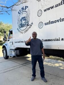 Happy customer giving a thumbs up next to a USF Moving Company truck after a successful local move in Houston