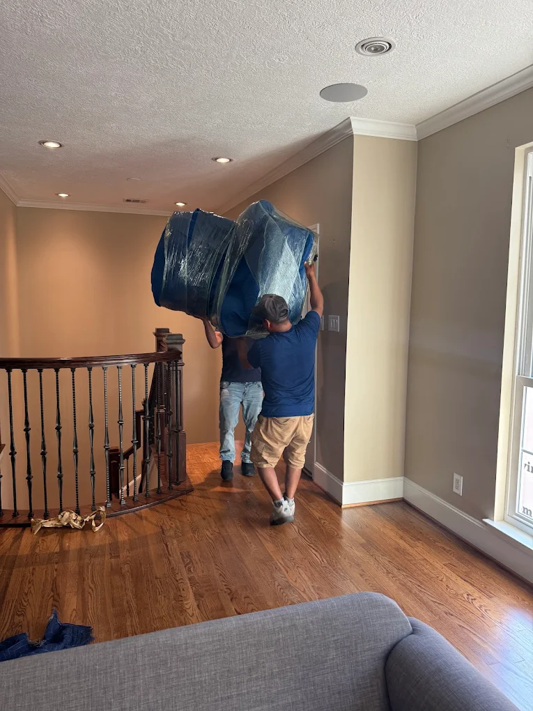 USF Moving Company team performing a careful, professional furniture move down a staircase in a residential home.